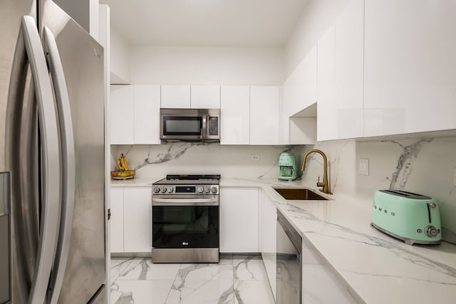 kitchen with tasteful backsplash, white cabinets, stainless steel appliances, and a sink