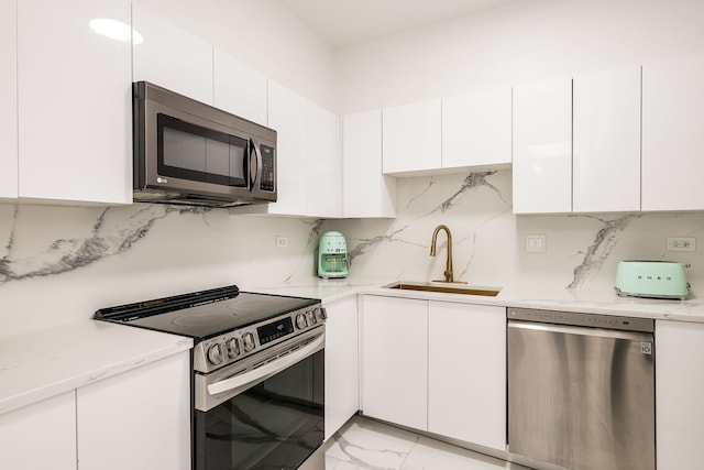 kitchen with backsplash, appliances with stainless steel finishes, marble finish floor, white cabinetry, and a sink