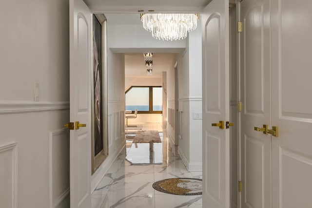 hall featuring a chandelier and marble finish floor