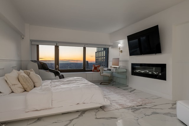 bedroom featuring marble finish floor and a glass covered fireplace