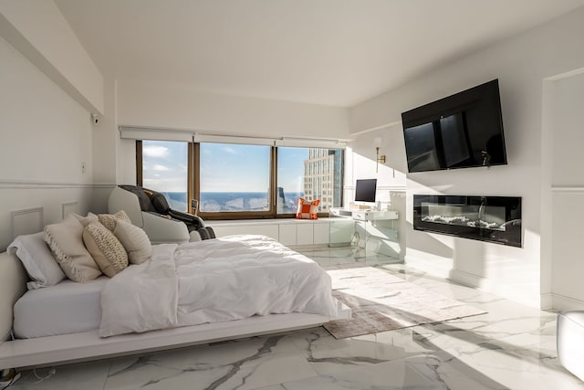 bedroom featuring a glass covered fireplace and marble finish floor