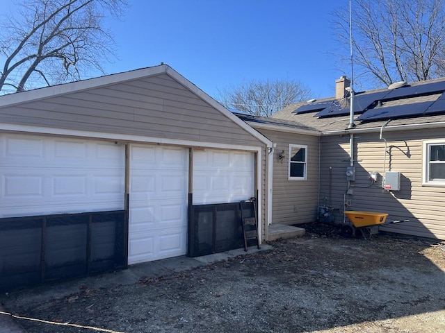 garage with solar panels and driveway