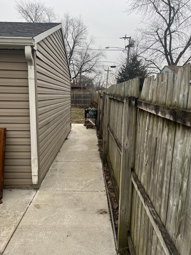 view of side of home with a shingled roof and a fenced backyard