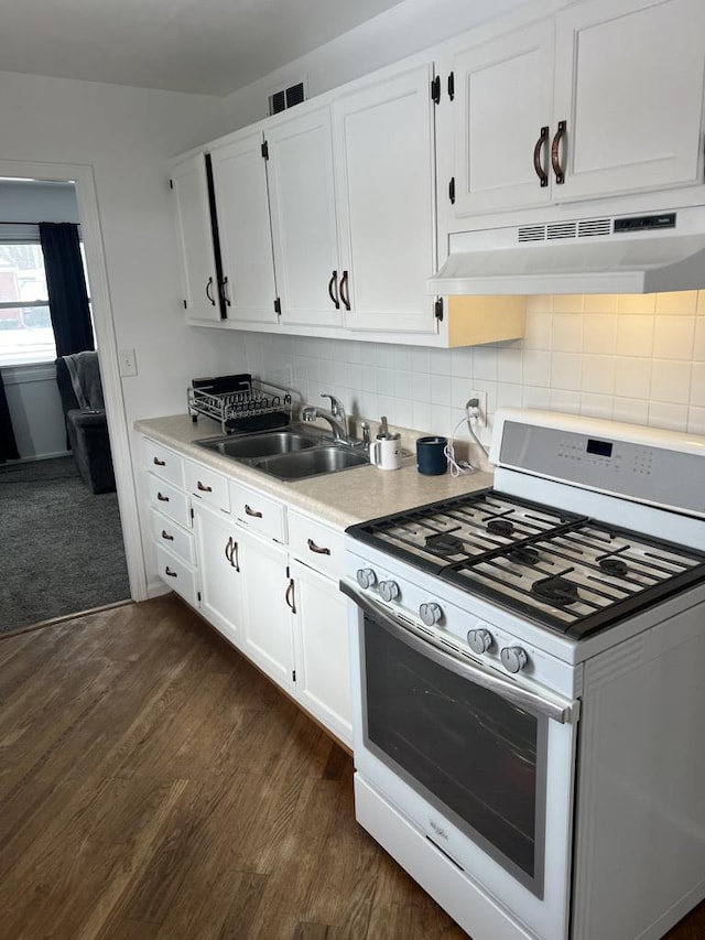 kitchen featuring under cabinet range hood, a sink, white cabinetry, gas range gas stove, and dark wood finished floors