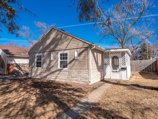 view of home's exterior with stone siding and fence