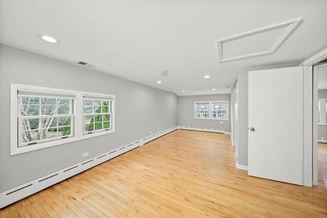 empty room with attic access, a baseboard heating unit, light wood-style flooring, and recessed lighting