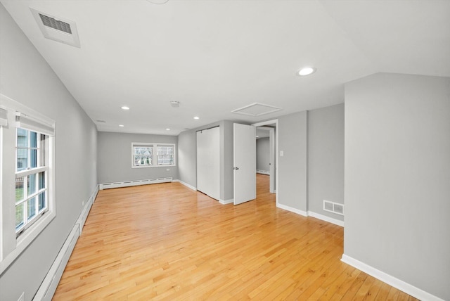 unfurnished room with baseboard heating, visible vents, and light wood-style floors