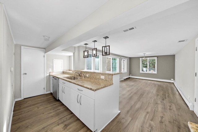 kitchen featuring visible vents, dishwasher, a peninsula, baseboard heating, and a sink