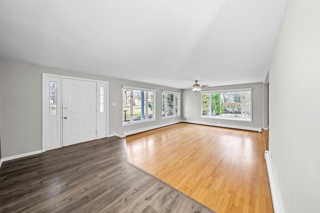 entryway with a baseboard heating unit, baseboards, and wood finished floors