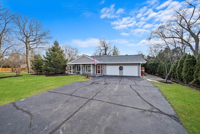 view of front of home with aphalt driveway, roof with shingles, a chimney, an attached garage, and a front yard