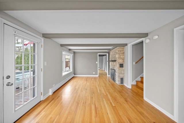 unfurnished living room featuring light wood-style flooring, a baseboard heating unit, a stone fireplace, beamed ceiling, and baseboards