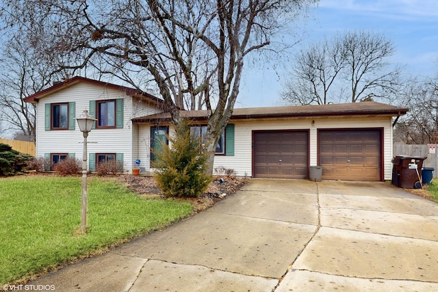 tri-level home with a front yard, driveway, an attached garage, and fence