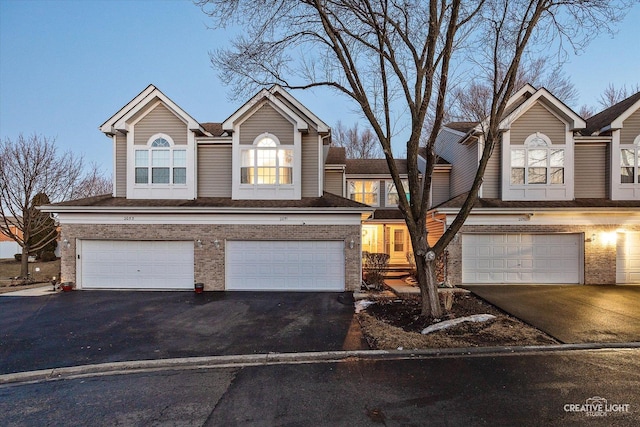 view of front facade featuring aphalt driveway, brick siding, and an attached garage