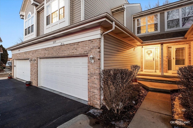 view of front facade with a garage, aphalt driveway, and brick siding