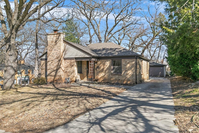 mid-century inspired home featuring an outbuilding, a chimney, brick siding, and roof with shingles