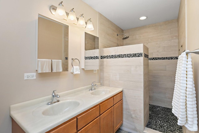 full bath with a tile shower, recessed lighting, double vanity, and a sink