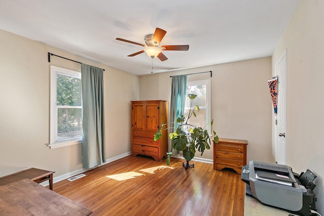 sitting room featuring a wealth of natural light, baseboards, wood finished floors, and a ceiling fan