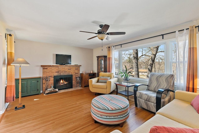 living area with light wood finished floors, a fireplace, and ceiling fan