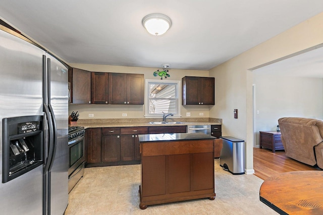 kitchen featuring dark brown cabinetry, appliances with stainless steel finishes, a kitchen island, and a sink