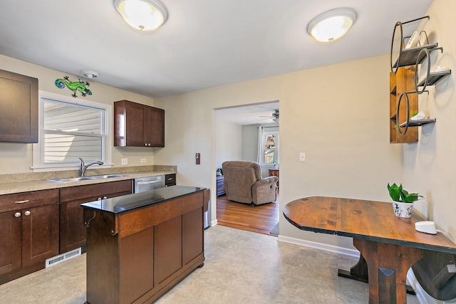 kitchen featuring visible vents, a kitchen island, a sink, dark brown cabinetry, and stainless steel dishwasher