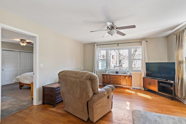 living room with baseboards, light wood-type flooring, and ceiling fan