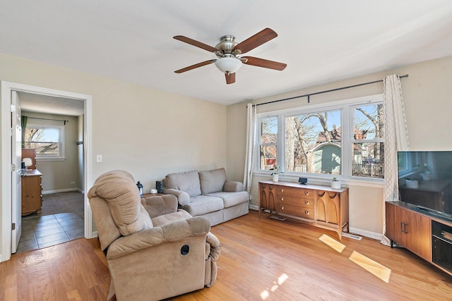 living room featuring light wood finished floors, ceiling fan, and baseboards