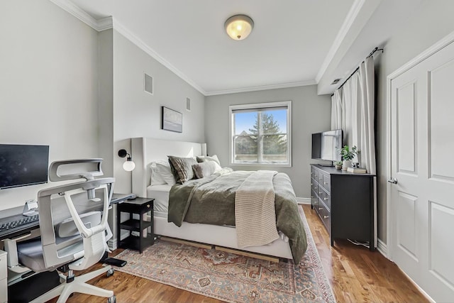 bedroom featuring light wood-style floors, visible vents, and crown molding