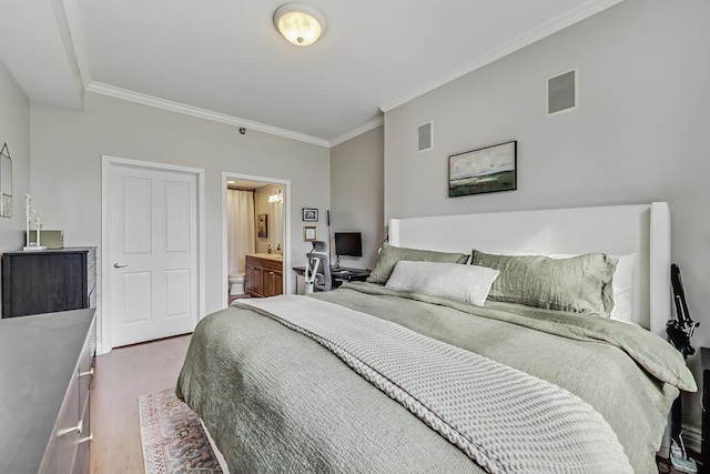 bedroom with ornamental molding, visible vents, ensuite bath, and wood finished floors