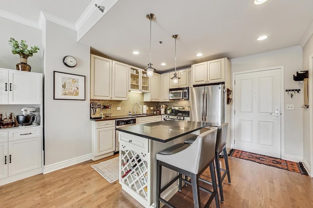 kitchen featuring a breakfast bar, light wood-style floors, appliances with stainless steel finishes, dark countertops, and crown molding