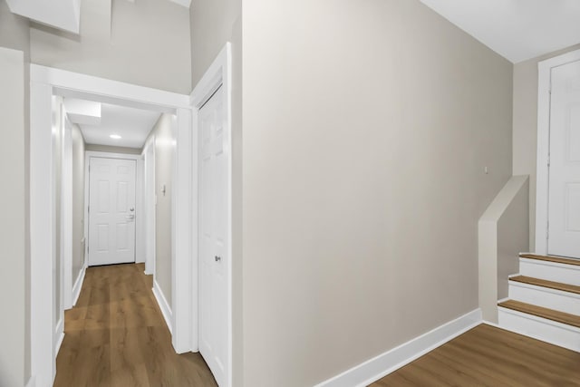 hallway with stairway, baseboards, and wood finished floors