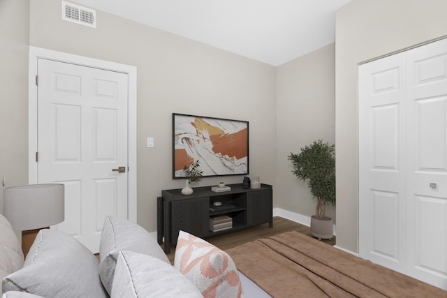 bedroom featuring a closet, wood finished floors, visible vents, and baseboards