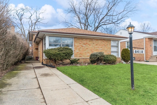 view of home's exterior featuring a shingled roof, brick siding, and a yard