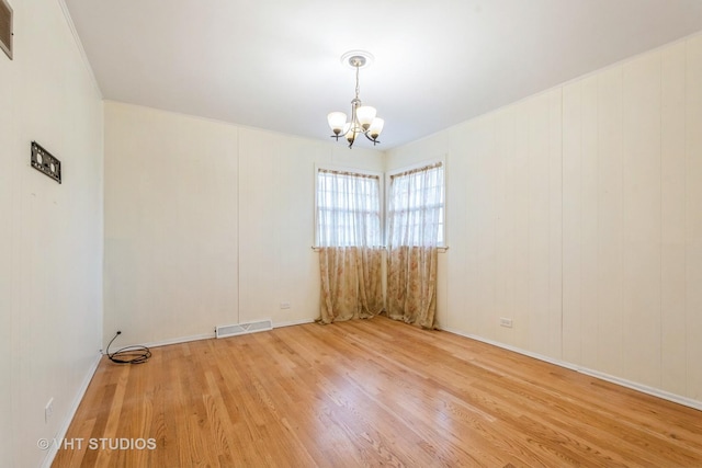 unfurnished room featuring a notable chandelier, visible vents, and wood finished floors