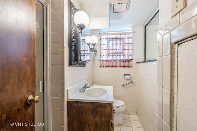 bathroom featuring toilet, tile patterned flooring, tile walls, and vanity