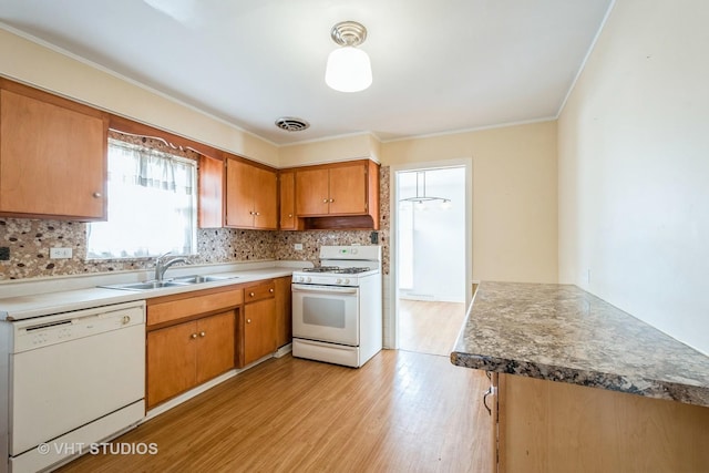 kitchen with light wood-style flooring, white appliances, a sink, visible vents, and decorative backsplash