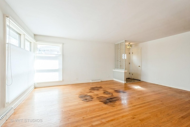 unfurnished living room featuring a baseboard heating unit, baseboards, visible vents, and light wood-style floors