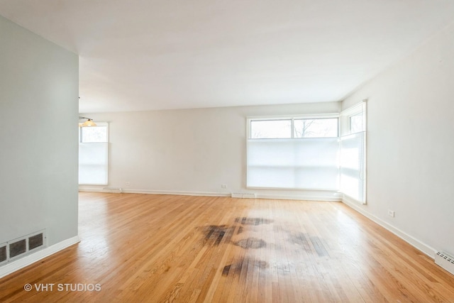 unfurnished room with light wood-style floors, baseboards, and visible vents