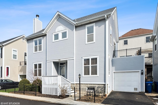 townhome / multi-family property featuring a garage, a chimney, fence, and aphalt driveway