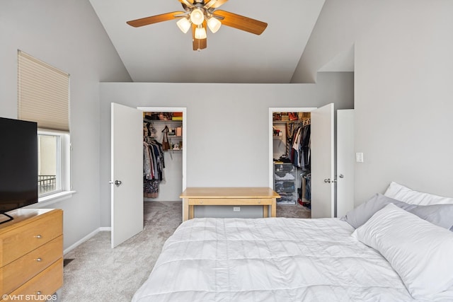 bedroom featuring light carpet, baseboards, a ceiling fan, lofted ceiling, and a walk in closet