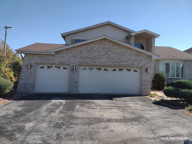 view of front of property featuring a garage, aphalt driveway, and brick siding