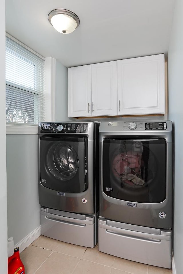 laundry area with light tile patterned flooring, independent washer and dryer, cabinet space, and baseboards