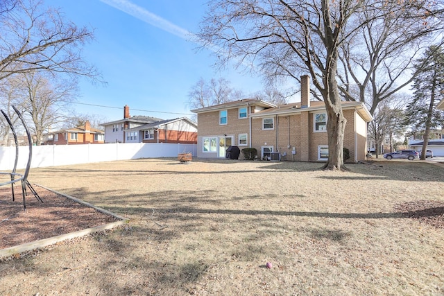 rear view of property featuring brick siding and fence