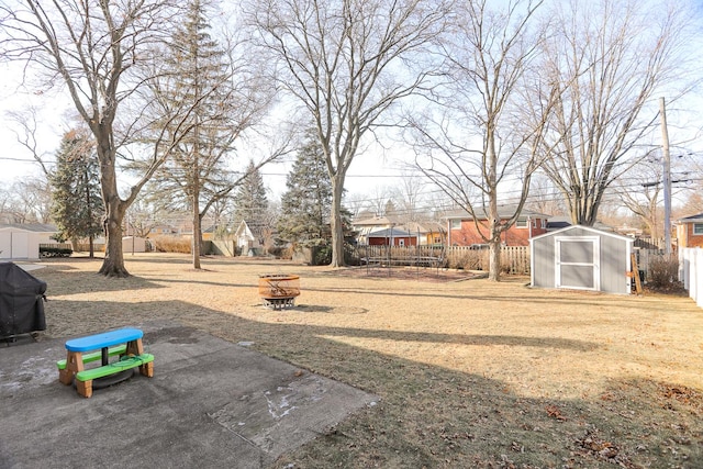 view of yard featuring an outbuilding, an outdoor fire pit, a fenced backyard, a residential view, and a shed