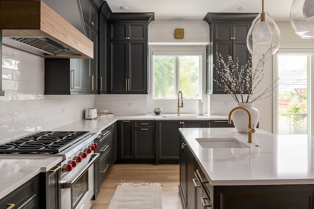 kitchen featuring light wood-type flooring, stainless steel stove, a sink, and custom exhaust hood