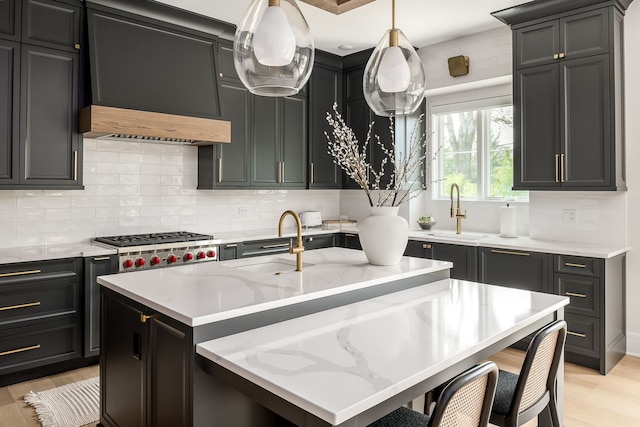 kitchen with light wood-style floors, a sink, backsplash, and light stone countertops