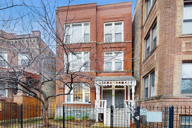 multi unit property with brick siding and a fenced front yard