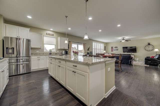 kitchen featuring dark wood-type flooring, stainless steel fridge with ice dispenser, a wealth of natural light, and a kitchen island