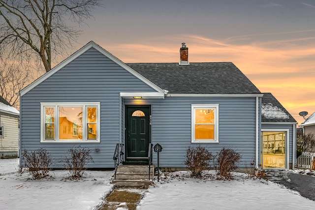 bungalow featuring entry steps, a shingled roof, and a chimney