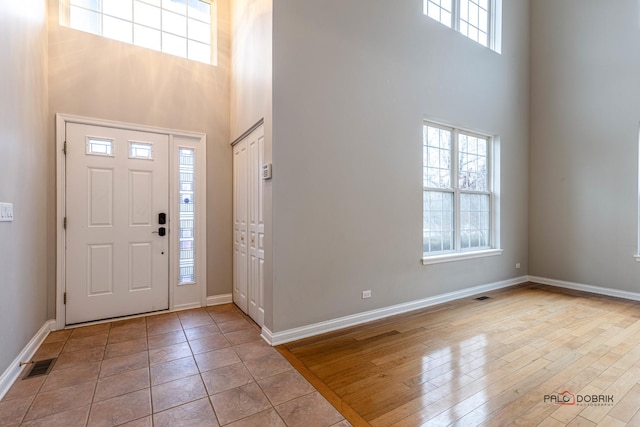 entryway with a towering ceiling, baseboards, and visible vents