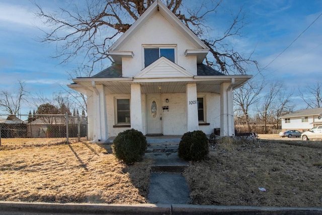 bungalow-style house featuring stucco siding, fence, a porch, and roof with shingles